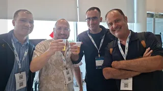 Four men with badges at an official conference connected to Bnei Baruch