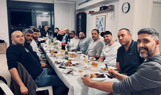 An informal evening dinner: about fifteen men from the Bnei Baruch circle at a shared table in a private apartment